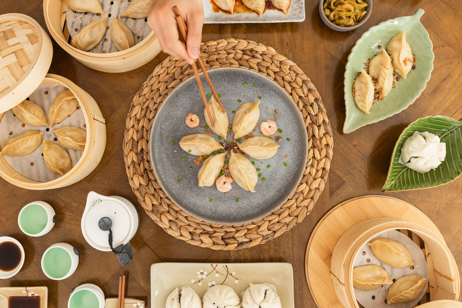 A generous Yum Cha table with cooked dumplings, bamboo steamers, tea and dipping sauces